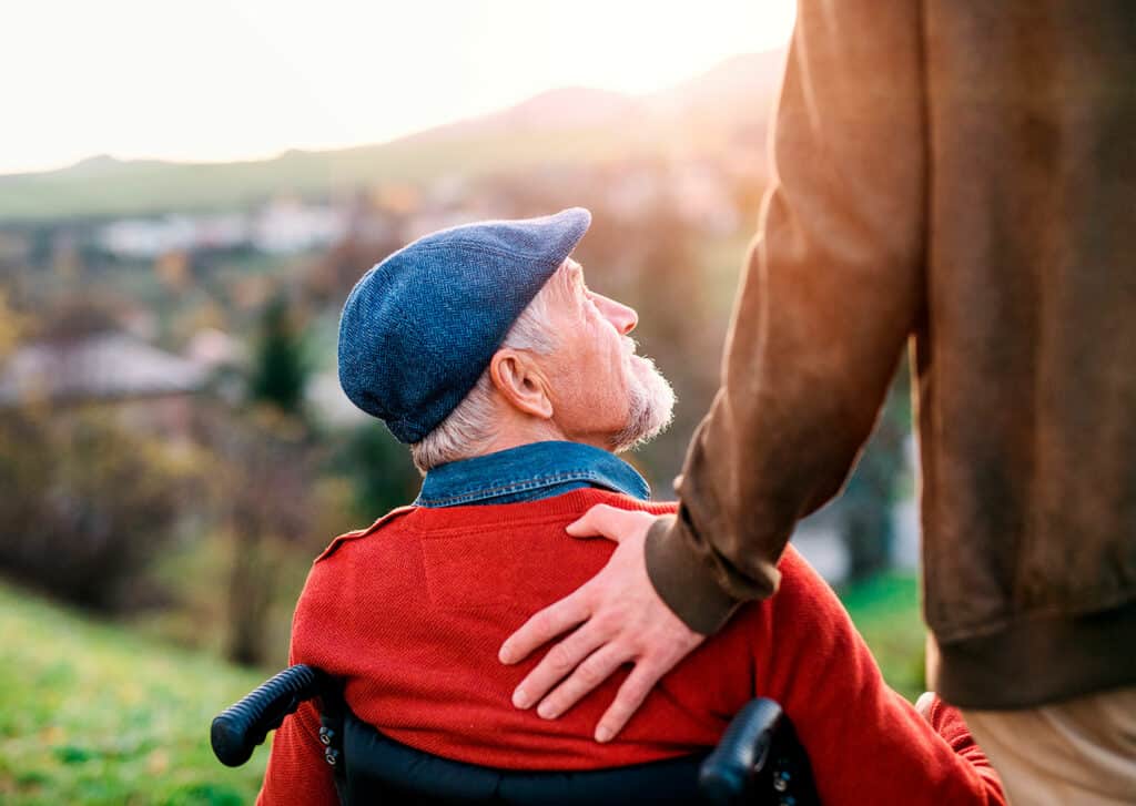 Man in wheelchair, with another man behind looking up at him